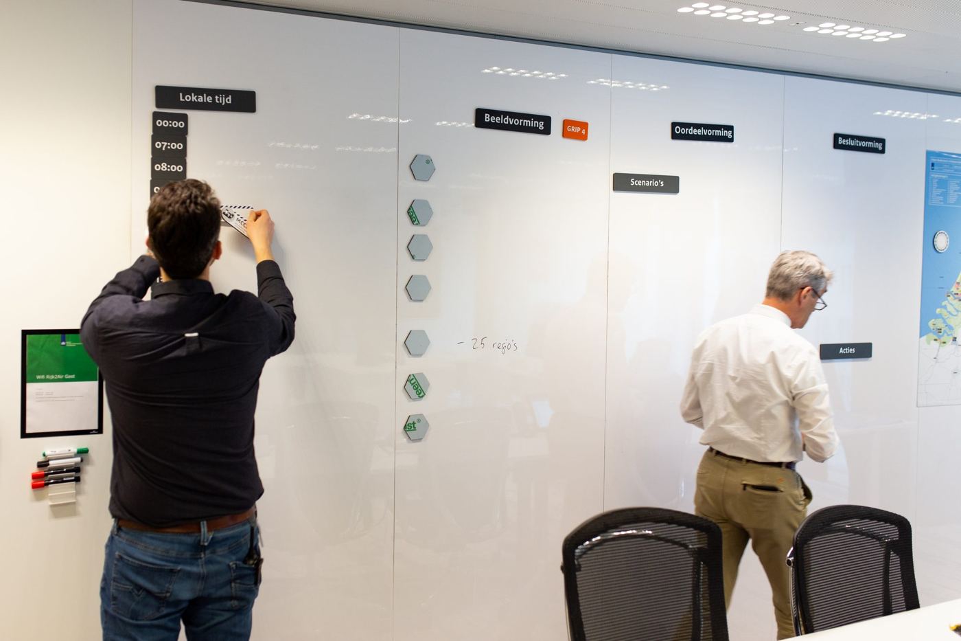 Medewerkers plaatsen magneten op de wand