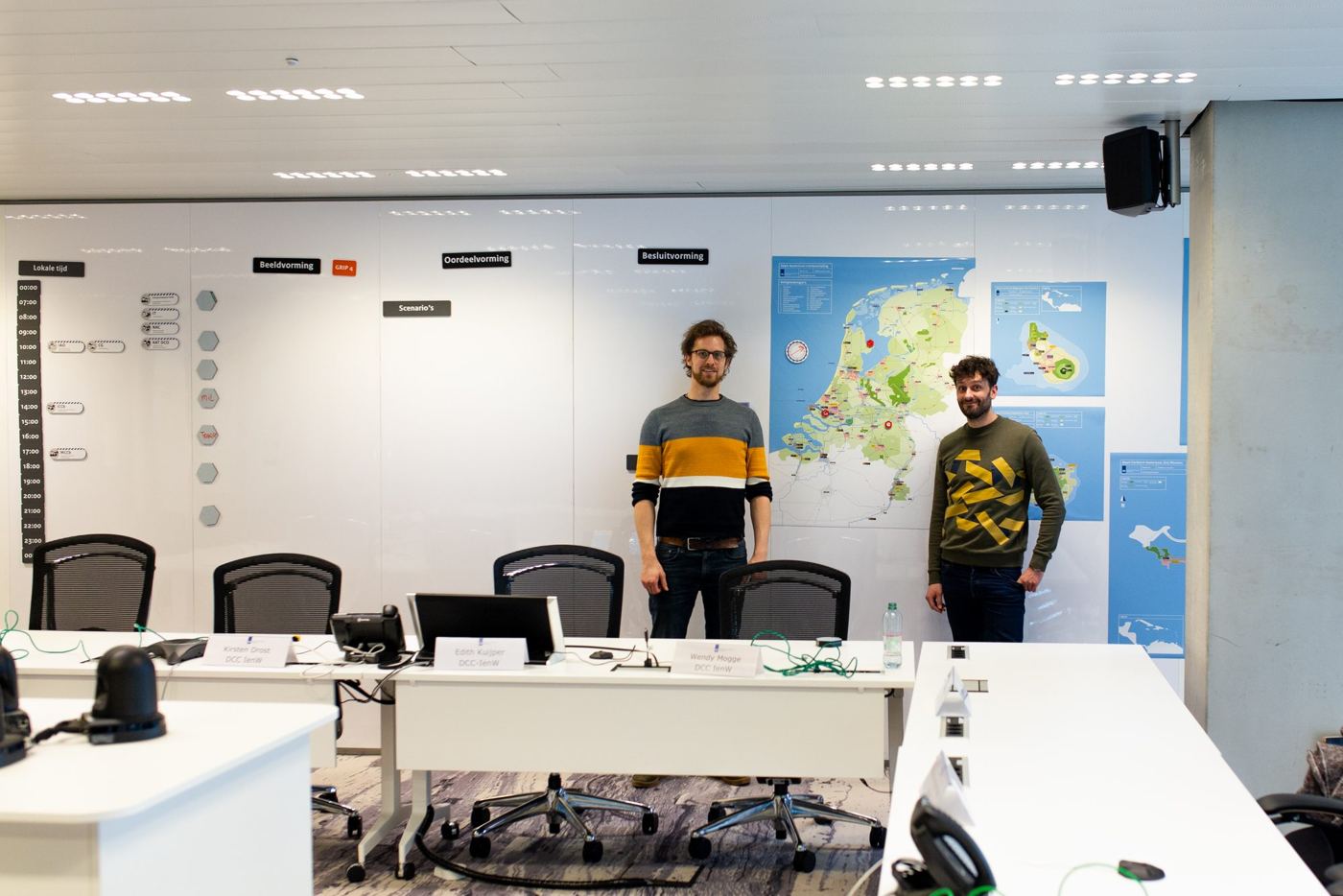 Twee medewerkers in de crisisruimte van DCC IenW voor de BOB-wand met kaart