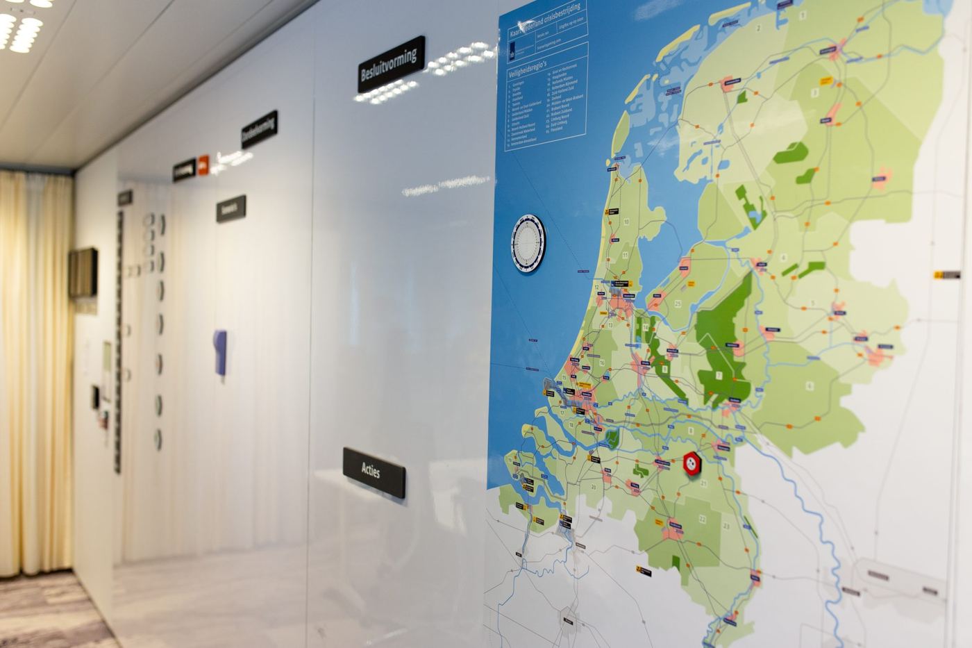 Crisisruimte van DCC IenW met een grote magnetische kaart van Nederland en BOB-titels op de whiteboardwand