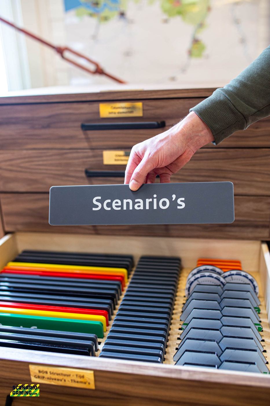 Een hand pakt de titel Scenario's uit een lade