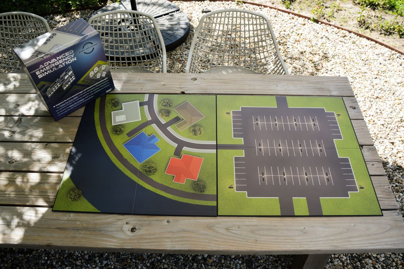 Spelbord met een industrieterrein en een parkeerterrein op een tuintafel, met de doos erachter