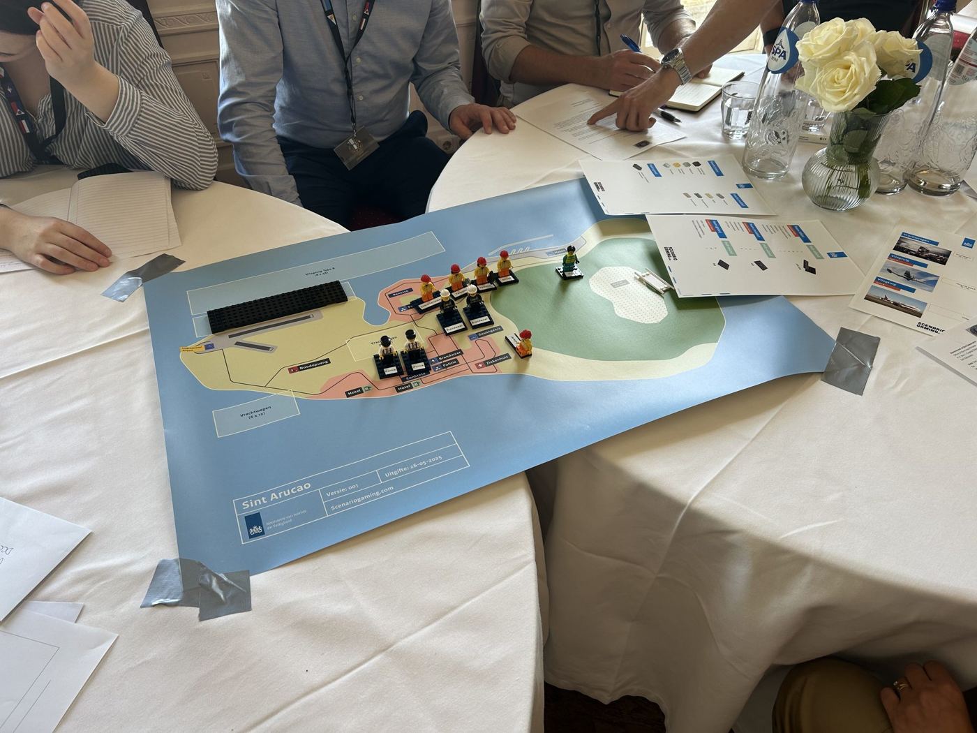 Spelbord met een eiland en legofiguren op een ronde tafel tijdens de oefening
